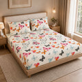 A bed dressed in a cream-colored sheet set with a vibrant multicolor butterfly print, styled in a warm, modern bedroom setting with wooden furniture and natural light.
