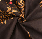 Dark fabric with gold leaf embroidery and a red button